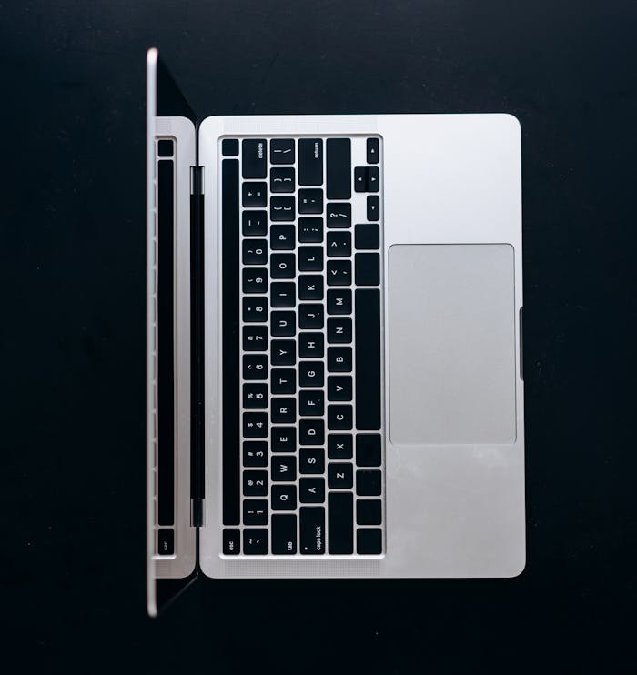High-angle shot of an open laptop on a black background showcasing minimalist design.